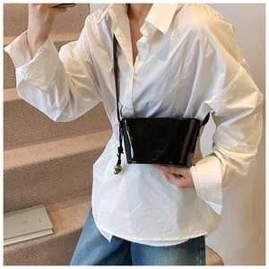 Détail du sac seau en cuir verni noir brillant avec breloque cœur argentée et bandoulière