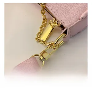 Close-up of pink litchi grain leather bag with gold lobster clasp and metal chain detail