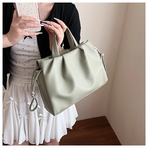 Detail shot of light green pleated handbag showing soft leather texture and drawstring knots