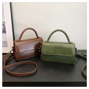 Detail of vintage glossy leather crossbody bags in coffee brown and olive green colors