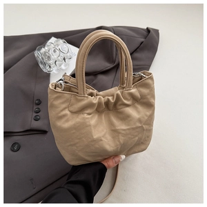 Detailed shot of beige ruched bucket bag with soft leather texture and handle details