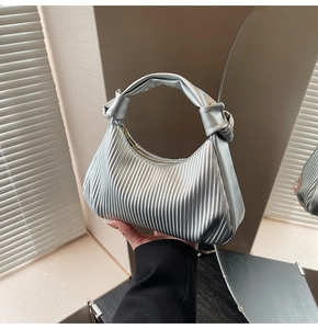 Detail of silver pleated handbag with knot handle and modern metallic finish