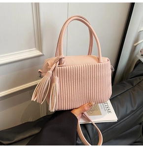 Détail d'un sac seau rose clair avec texture plissée et pompon décoratif élégant