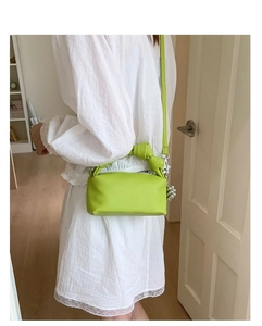 Close-up of grass green pebbled leather bag featuring a knotted handle and silver charms