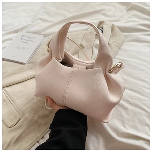 Detail of light pink pleated handbag with litchi texture and gold metal hardware