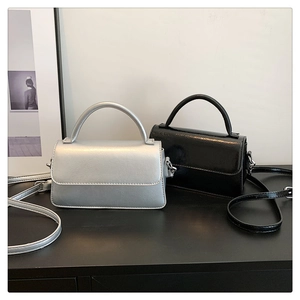 Detail of minimalist silver and black crossbody bags with sleek glossy finish and handles