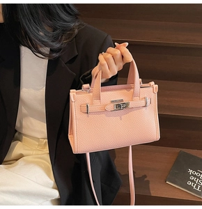 Détail du sac à main en cuir grainé rose avec fermoir argenté et bandoulière amovible
