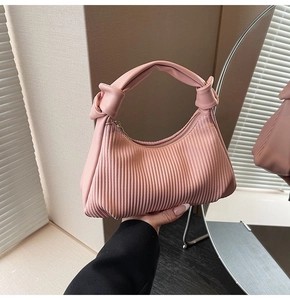 Close-up of pink pleated pea bag with knotted handle and elegant gold zipper detail