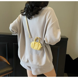 Detalle de micro bolso bowling amarillo en modelo con ropa casual gris de gofre