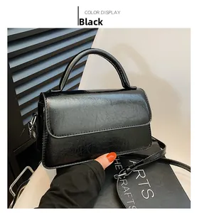 Close-up of black glossy crossbody bag showing textured finish and adjustable strap