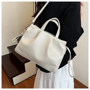 Detail of a beige ruched crossbody bag with lychee grain texture and side knot decor