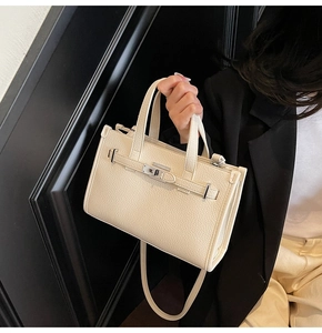 Détail de la texture grainée et du fermoir métallique rotatif du sac à main crème
