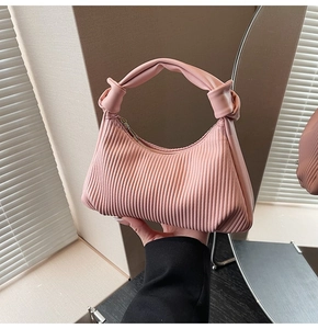Detail of pink pleated pea bag with a unique knot handle and golden zipper hardware