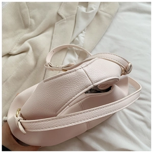 Close-up of pink cloud bag with lychee grain texture and light gold metal strap buckles