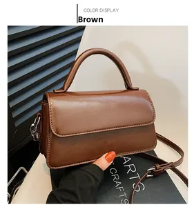 Detail of brown leather handbag with silver metal hardware and detachable strap