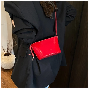 Vue de dos d'un mannequin portant un sac seau en cuir rouge brillant sur un blazer noir