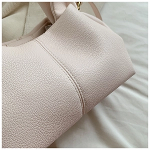 Detailed close-up of light pink lychee grain leather with premium double stitching