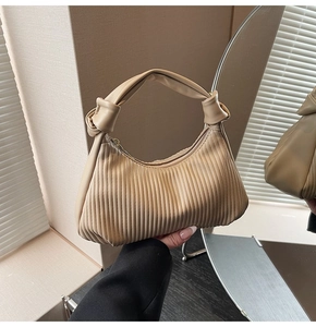 Detail of pleated beige moon bag featuring a knotted handle and vertical textured finish