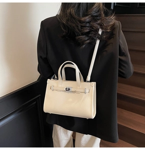 Détail d'un sac bandoulière en cuir beige avec fermoir rotatif argenté et sangle