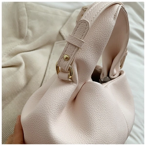 Close-up of pink leather handbag showing lychee grain texture and gold hardware details