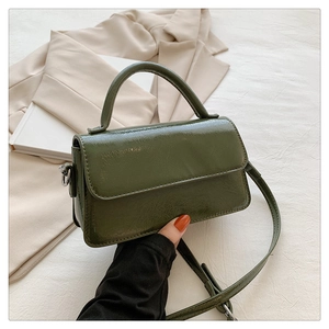 Close-up of vintage dark green crossbody bag with glossy texture and silver hardware