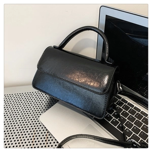 Detail of vintage black patent PU leather small square bag with pleated texture and silver hardware