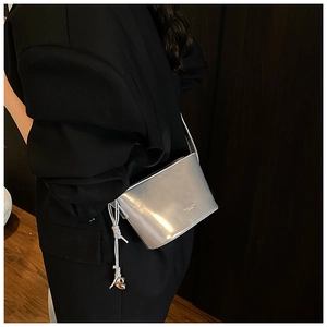 Détail du sac seau argenté avec pendentif cœur, cordon de serrage et logo brillant
