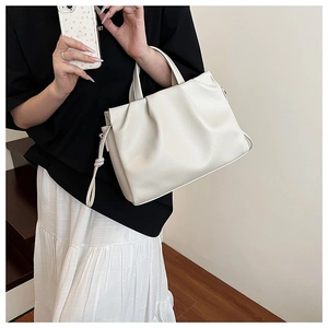 Detail der beige Falten-Tasche aus weichem Leder mit elegantem Griff und feiner Struktur