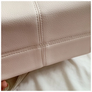 Macro detail of high-quality cross-stitch sewing on lychee textured beige leather bag