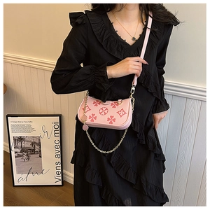 Detailed shot of pink crossbody bag with clover pattern and gold chain on model