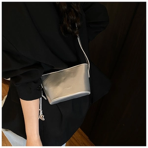 Gros plan du mini sac seau argenté en cuir texturé avec logo sur un blazer noir