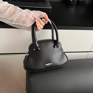 Primo piano di una borsa nera in pelle a grana con dettagli argentati tenuta da modella