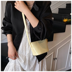 Détail du sac seau crème à motif litchi avec finition brillante et bandoulière fine
