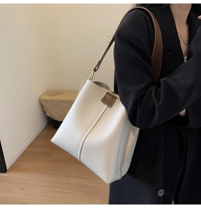 Detail of creamy white bucket bag featuring grainy leather texture and brown strap