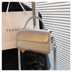 Close-up of silver textured leather mini square bag on mannequin with shoulder strap