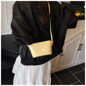 Détail du sac à bandoulière brillant de couleur crème avec fine bandoulière
