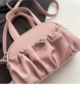 Detail of pink pleated handbag with metal clasp and soft PU leather texture