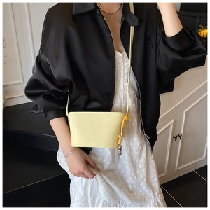 Détail du sac seau jaune pâle à texture litchi avec ornement en boule métallique