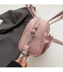 Detail showing high-quality silver metal buckle and pink rabbit ear decor on textured bag