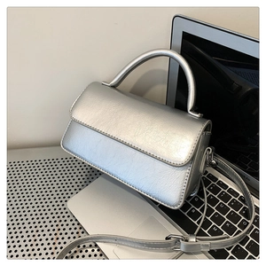 Detail of silver metallic PU leather handbag with wrinkled texture and adjustable strap