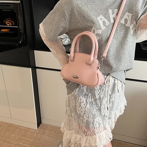 Dettaglio di una mini borsa rosa in pelle martellata con doppi manici e tracolla sottile