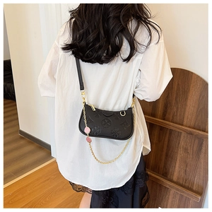 Close-up of black embossed clover pattern leather and golden chain on shoulder bag