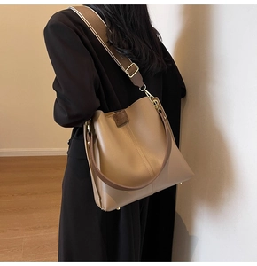 Detail of khaki bucket bag with wide woven strap and embossed leather brand logo