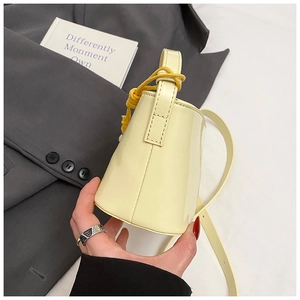Détail du sac seau en cuir verni jaune clair avec poignée à nœud tressé et couture fine