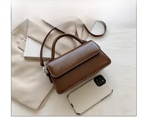 Detailed size comparison of the vintage brown crossbody bag next to a smartphone