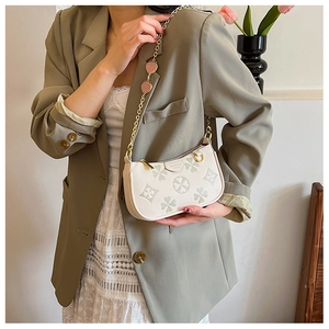 Detail of off-white leather bag with four-leaf clover print and strawberry pendants