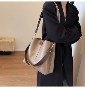 Detail shot of camel bucket bag with dark brown strap and premium gold hardware