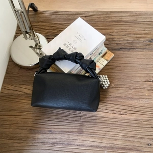 Minimalist black litchi pattern Boston handbag with stylish knotted handle and silver charm