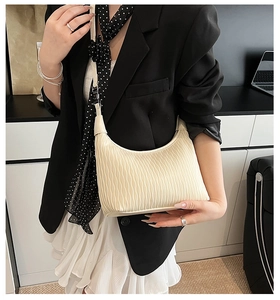 Detail of off-white pleated dumpling bag with elegant wavy texture and crescent shape
