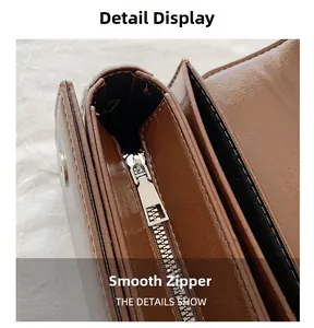 Detail of smooth silver zipper and glossy brown leather texture on handbag